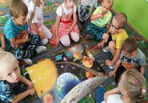 Dzieci oglądają układ słoneczny na ilustracji.